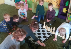 Dzieci układają figury szachowe na szachownicy